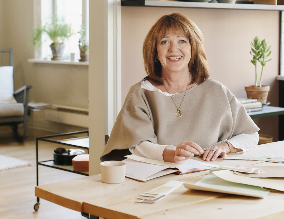 FARGESJEF: Lisbeth Larsen er global fargesjef i Jotun. Portrett i malt interør. Larsen sitter ve det bord med fargeprøver.