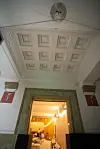 Historisk døråpning med ornamentert tak og opplyst rom under rehabilitering.