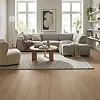 Lys stue med stort hjørnesofa, teppe og lyst trelignende gulv i åpen sone.