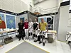 En gruppe malere står ved arbeidsstasjoner i en lys konkurransehall med dekorerte vegger.